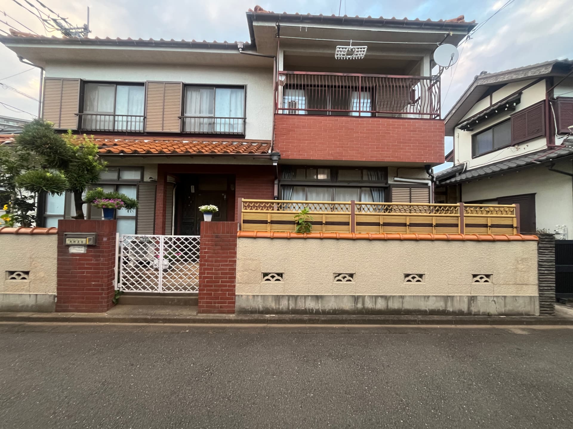 Front view of Hunter Cort's grandmother's two-storey house in Tokyo, with tiled roof and brick wall