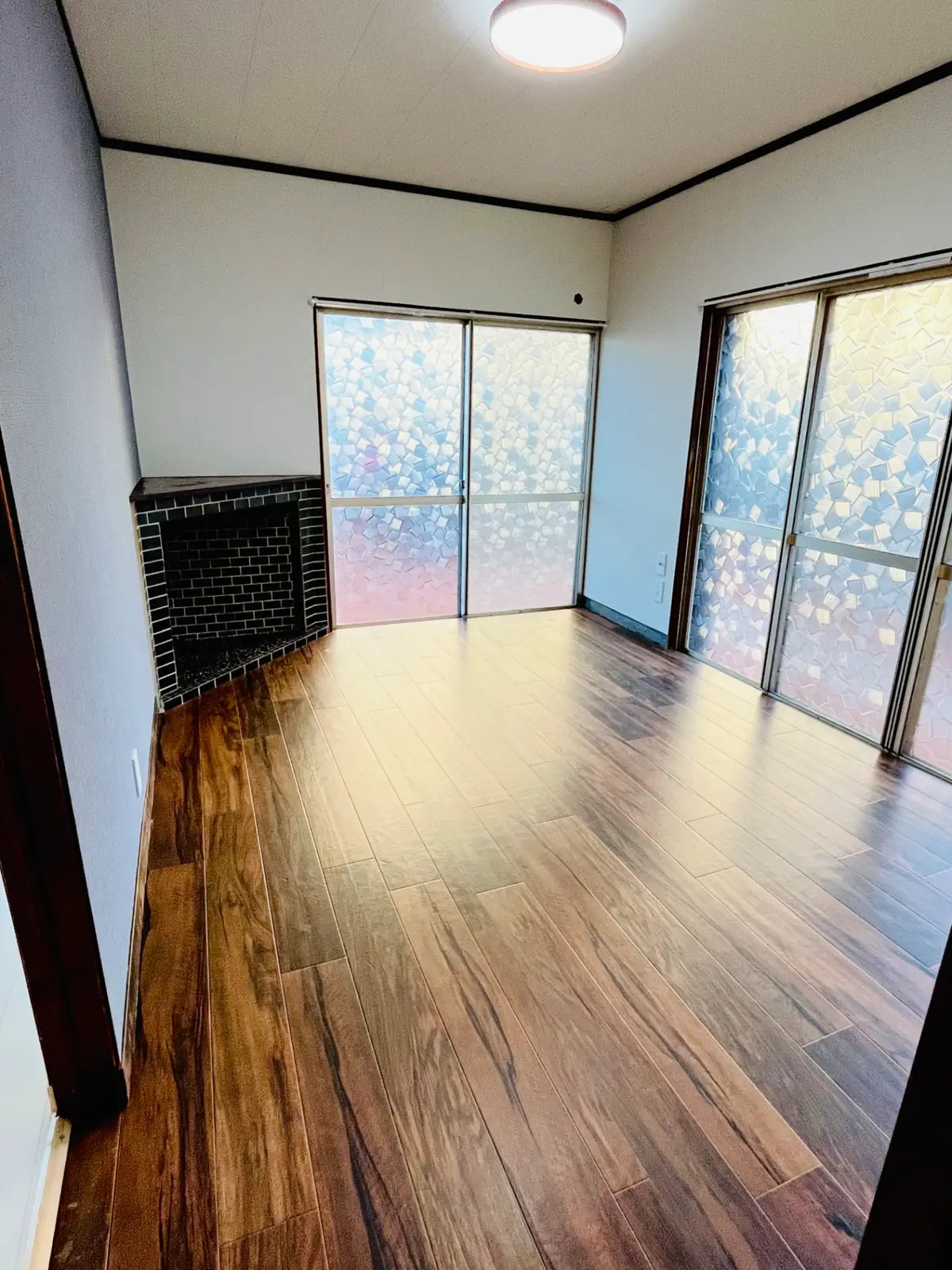 The same living room after renovation, with fresh light walls and new dark timber flooring